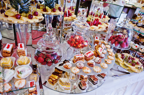 Wedding reception table with different fruits, cakes and sweets.