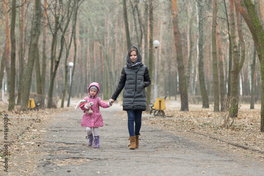 Mom and daughter are walking around the park in the hand Mom and daughter are walking around the park in the hand