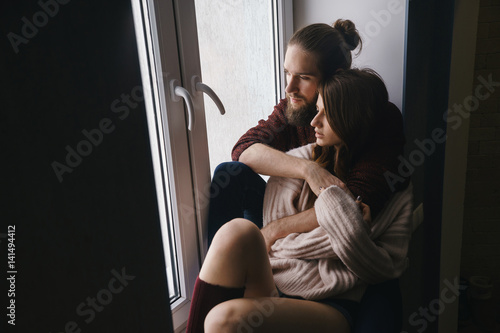 Sensual couple sitting on window sill