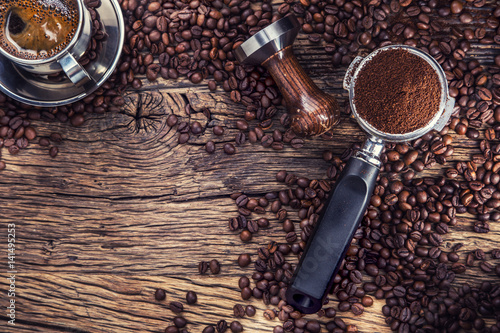 Kawa. Czarna kawa z ziaren kawy i portafilter na starym dębowym drewnianym stole.