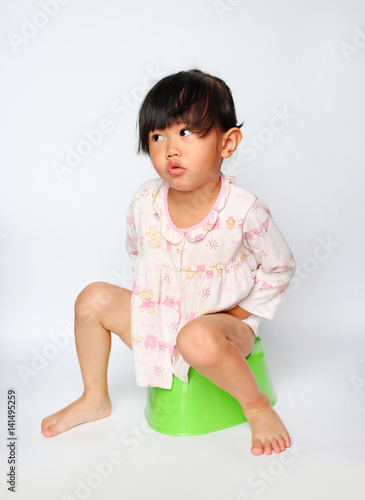 Little girl sitting on toilet training potty on white background