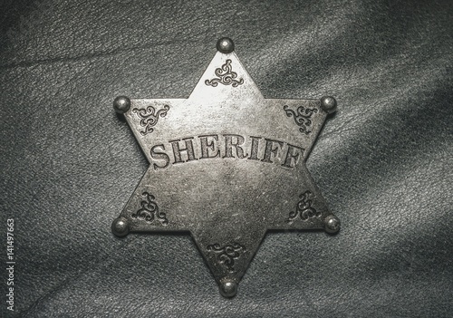 Sheriff badge on gray leather texture background. Macro shot.