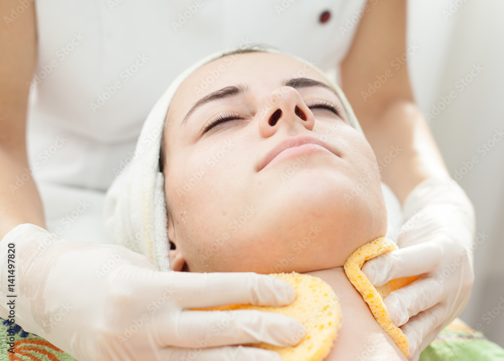Skin treatment.Beautician at spa makes facial treatment to a beautiful young woman Skin treatment.Beautician at spa makes facial treatment to a beautiful young woman
