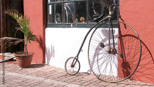 Old velocipede standing beside traditional building in small town of Saint George, Bermuda. photo