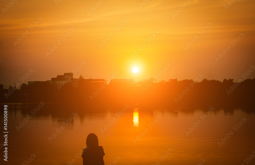 Woman sit near lake at sunset/ sunrise,selective focus,silhouette.