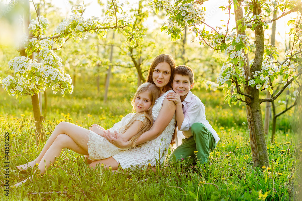 Fototapeta premium Beautiful young family in a blooming spring garden.