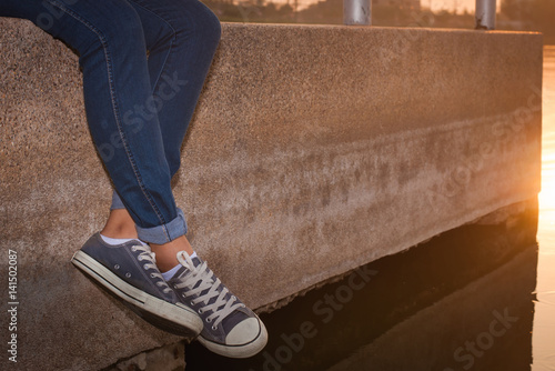 Woman legs hanging at lake in park for relax.