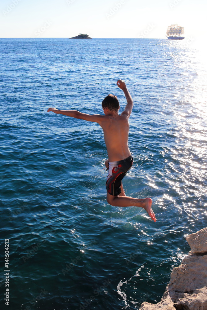 Kind springt von Klippe ins Meer