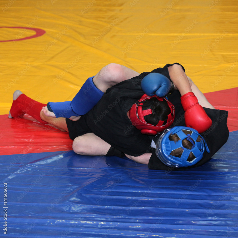 Φωτογραφία Young fighters in sports protection on the wrestling mat cover