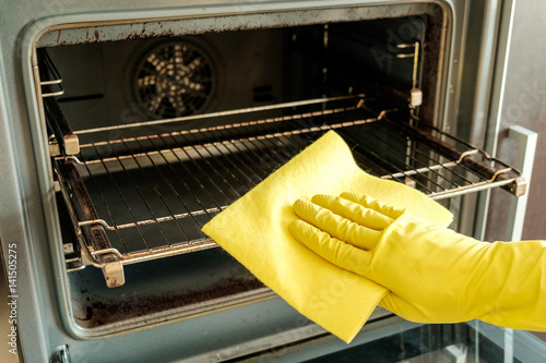 Male hand with gloves cleaning oven