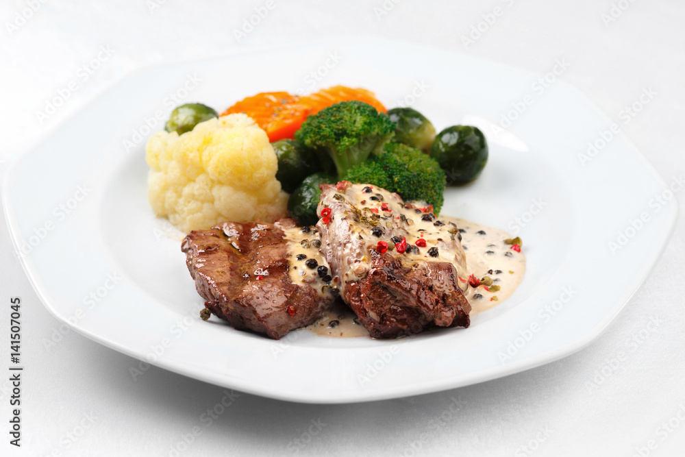 Grilled meat and steamed vegetables in a white plate Grilled meat and steamed vegetables in a white plate