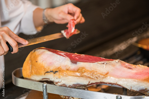 Chef slices serrano ham. Jamon Serrano. Typical Spanish delicatessen