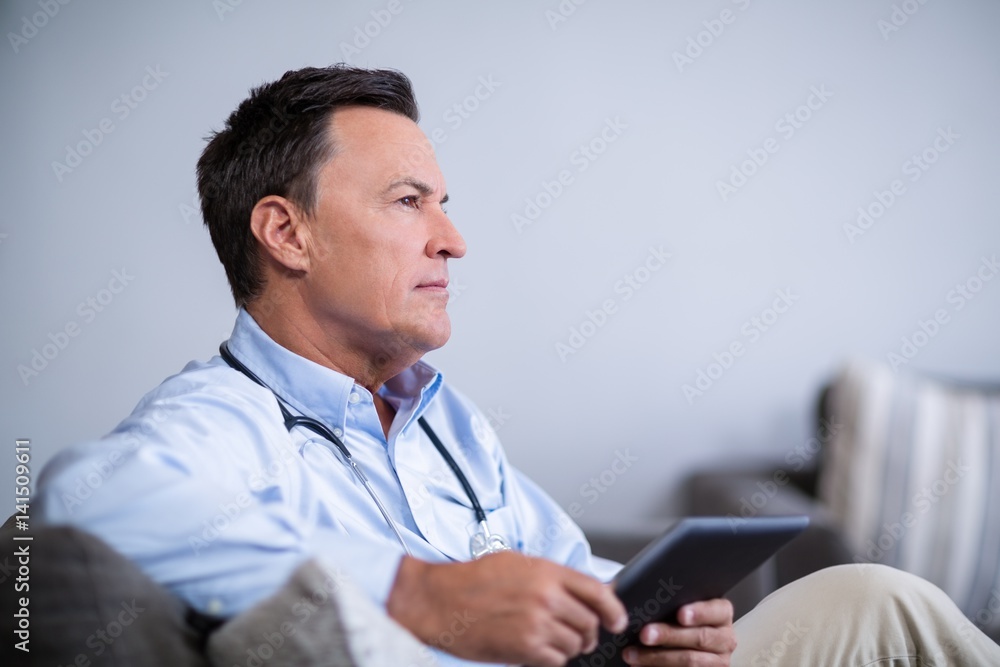 Thoughtful doctor holding digital tablet