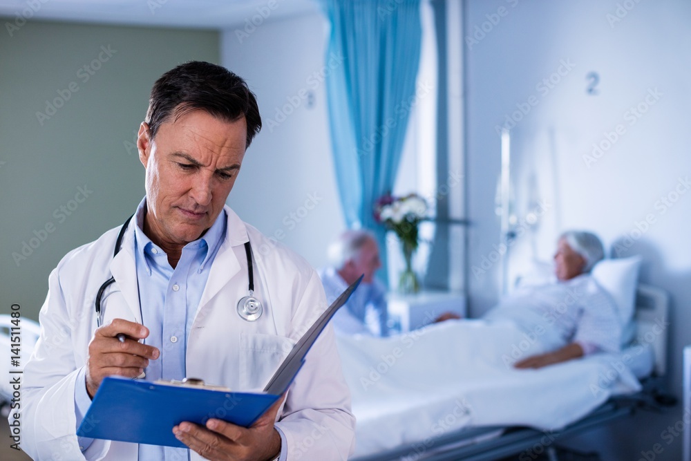 Male doctor looking at medical report Male doctor looking at medical report