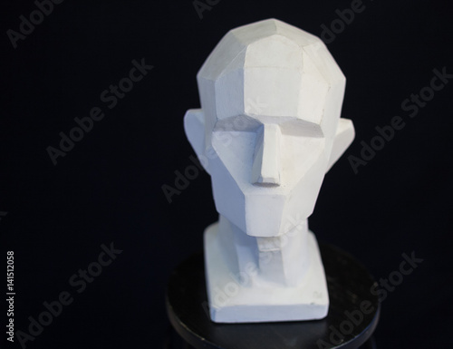 plaster bust of the person on a black background in style a cubism. concept of the person. empty space for the text. fullface of the person. model of the head of the human. photo