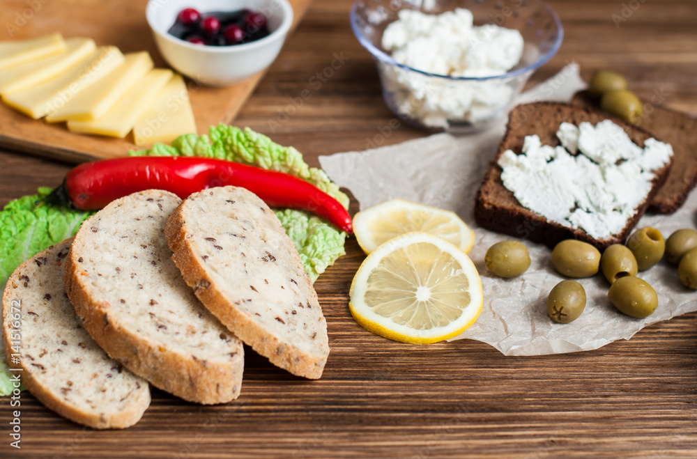 A sandwich with cheese and butter for breakfast, bread and pastries on the table. Wooden, dark background. Banner for a bakery. A sandwich with cheese and butter for breakfast, bread and pastries on the table. Wooden, dark background. Banner for a bakery.