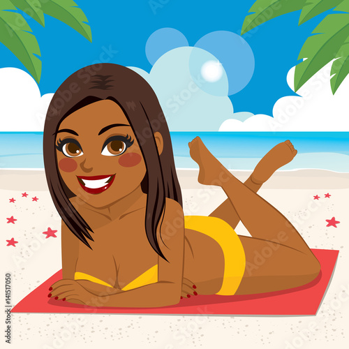 Beautiful young African American brunette woman lying on towel at beach