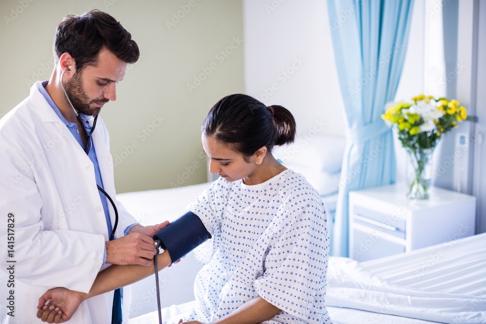 Fototapeta premium Male doctor checking blood pressure of a female patient