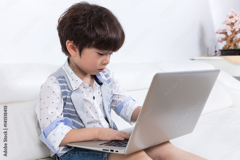 Asian Chinese little boy sitting on the couch with laptop Asian Chinese little boy sitting on the couch with laptop