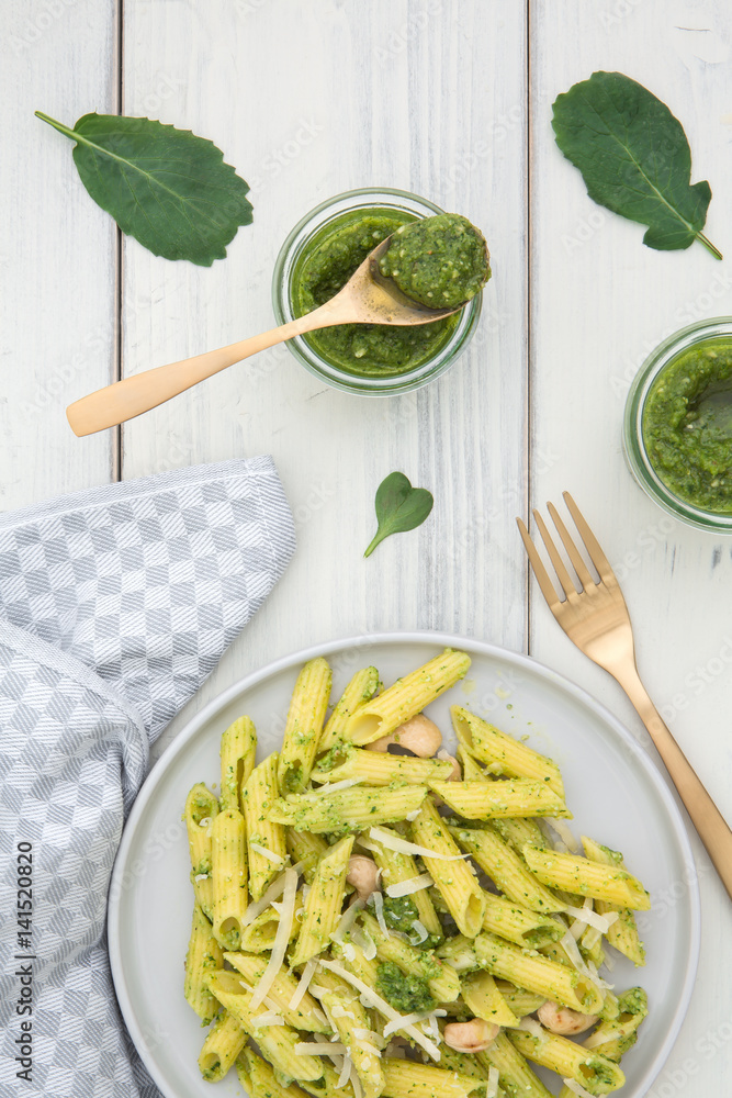 Teller mit Pasta und Pesto aus Radieschengrün auf einem alten weissen Holzuntergrund