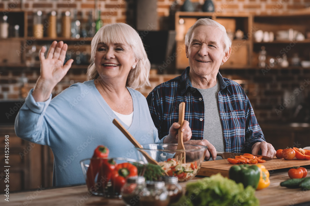 portrait of smiling senior couple making salad together portrait of smiling senior couple making salad together
