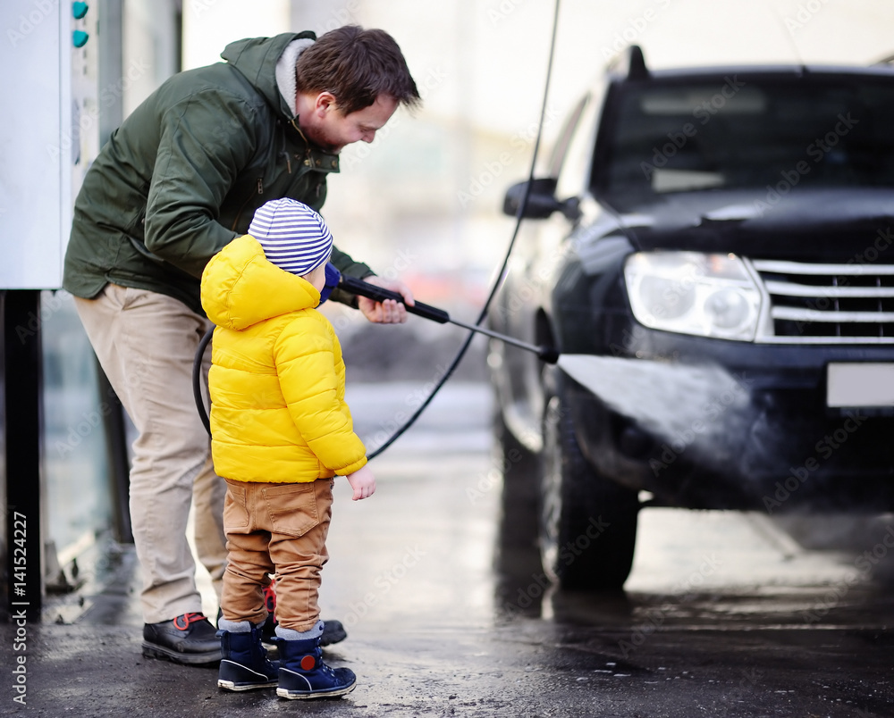 Middle age man and his little son washing a car on a carwash Middle age man and his little son washing a car on a carwash