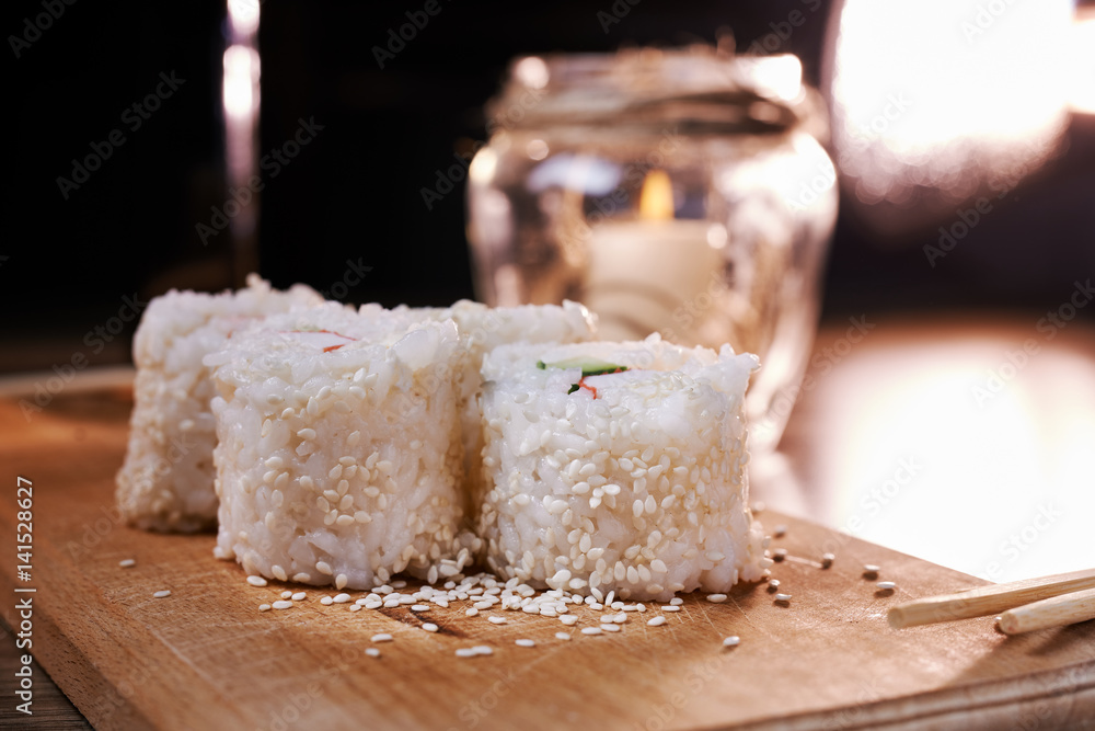 Japanese food, sushi roll with crab, sesame seeds, cucumber, cheese, on a wooden board Japanese food, sushi roll with crab, sesame seeds, cucumber, cheese, on a wooden board