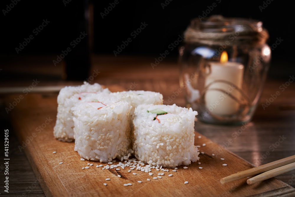 Japanese food, sushi roll with crab, sesame seeds, cucumber, cheese, on a wooden board Japanese food, sushi roll with crab, sesame seeds, cucumber, cheese, on a wooden board