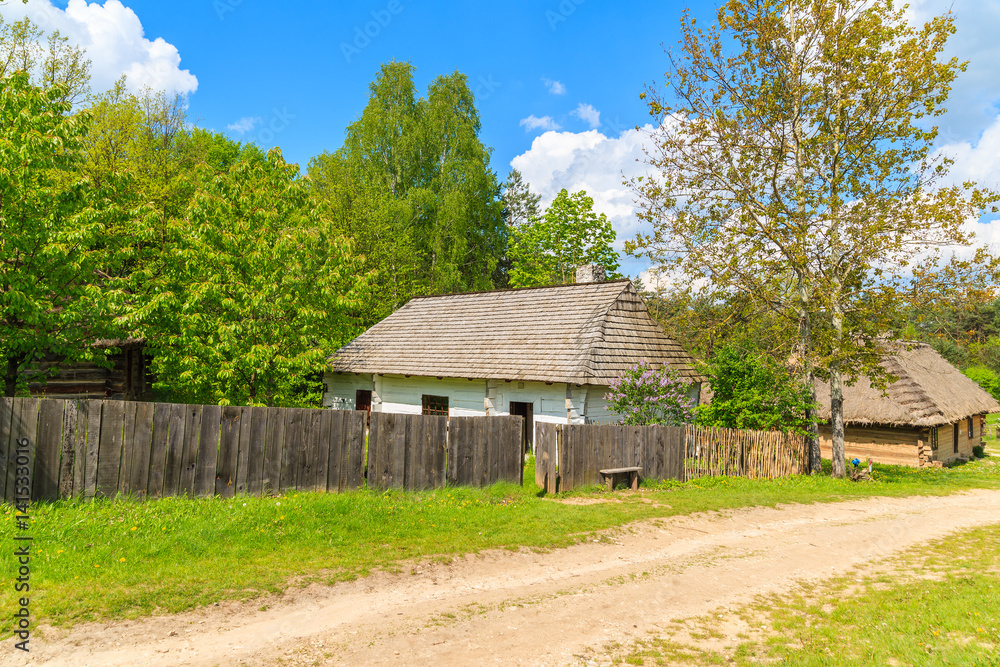 Rural road to Tokarnia village with straw roof houses on sunny spring day, Poland Rural road to Tokarnia village with straw roof houses on sunny spring day, Poland
