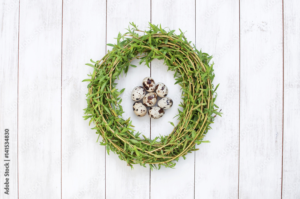 Easter composition of quail eggs in a nest of green willow branches on a white wooden background. Holiday concept with copy space view from above. Easter composition of quail eggs in a nest of green willow branches on a white wooden background. Holiday concept with copy space view from above.