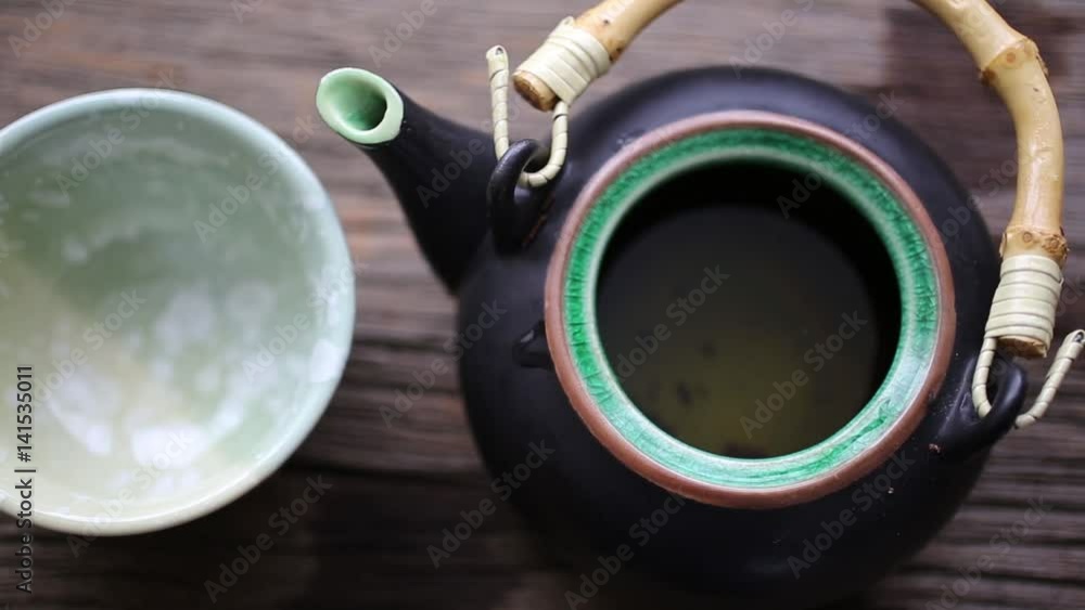Brewing tea in a little Asian teapot and pouring it into a cup. Brewing tea in a little Asian teapot and pouring it into a cup.