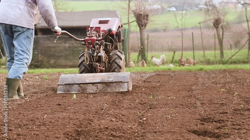 Farmer plowing the field with rototiller.  photo