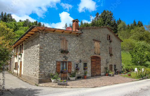 Traditional italian stone house near the road.Flowers on the windows and wooden shutters.Italy