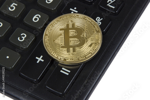 gold bitcoin lies on a black calculator