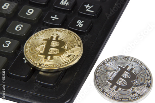 gold and silver bitcoin lies on a black calculator