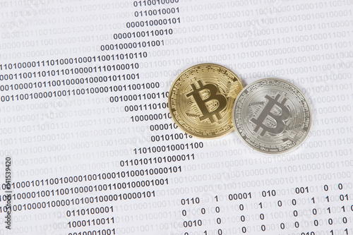gold and silver bitcoin on the background of binary code