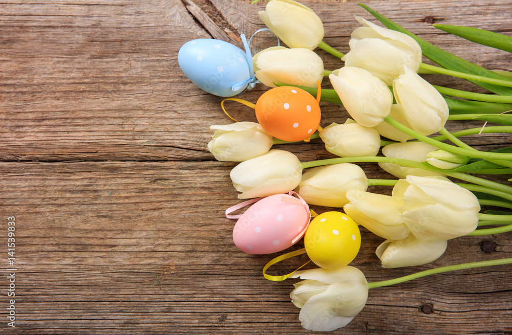 Easter eggs and tulips on wooden background and copy space