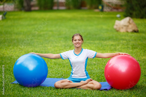 Sports girl doing fitness exercises with big fit ball on sand at beach. Fitness workout concept. Slim perfect body woman at green park photo