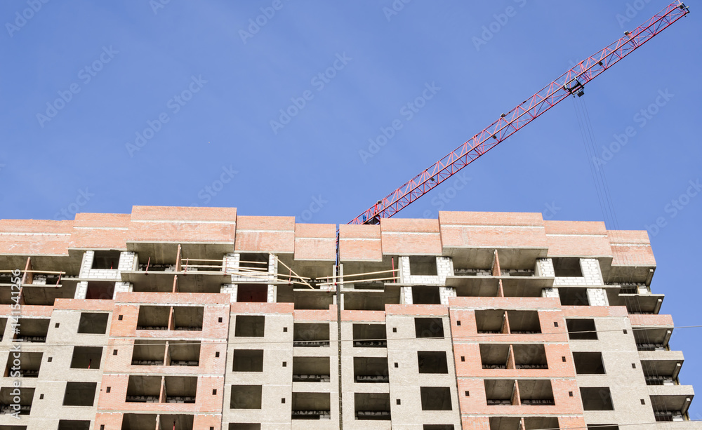 Fototapeta premium A red crane arrow over a high-rise building