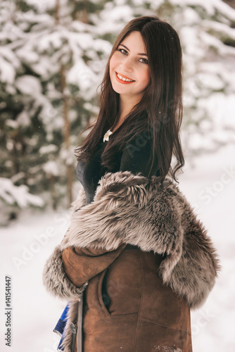 young beautiful girl in a fur coat walks in the Park