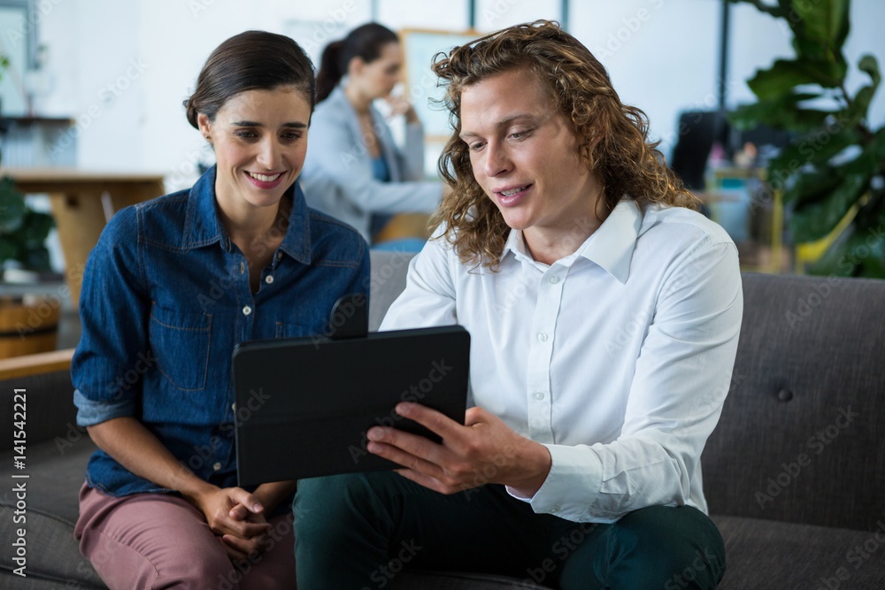 Smiling business colleagues discussing over digital tablet Smiling business colleagues discussing over digital tablet