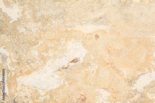 Texture of the old antique wall of yellow-sand color, there are fractures of the white protective layer of plaster from the effects of high humidity and atmospheric phenomena