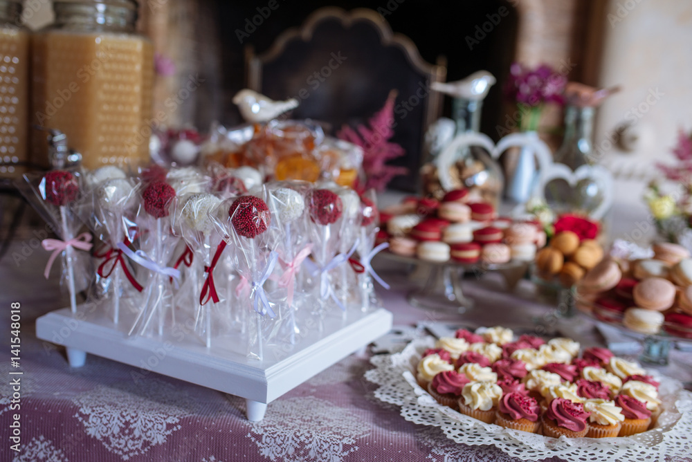 Beautiful multi colored decorated baked sweet tasty candy bar dessert party with happy people around, catering banquet table. macaroons