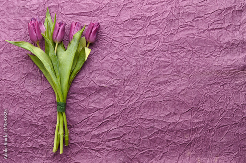 Spring purple tulips on creased wrapping paper background, top view
