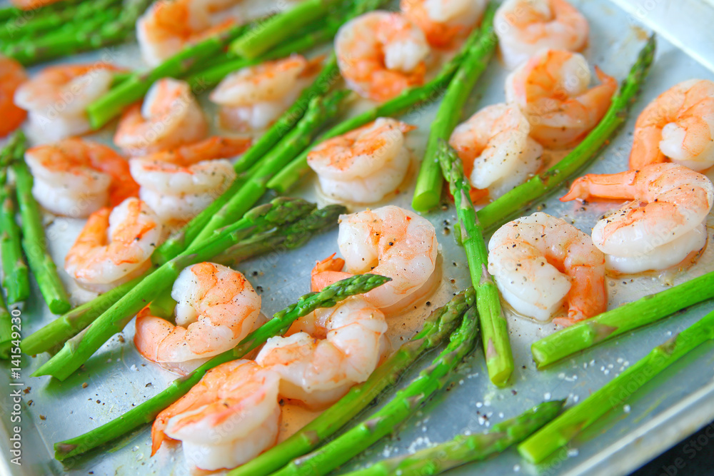 Fresh asparagus with shrimp on a baking sheet with coarse salt, olive oil and black pepper Fresh asparagus with shrimp on a baking sheet with coarse salt, olive oil and black pepper