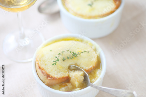 Small white bowls of onion soup with melted cheese toast and fresh thyme 