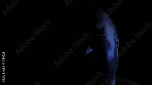 Mad insane crazy evil man laughing in darkness closeup. 4K UHD photo