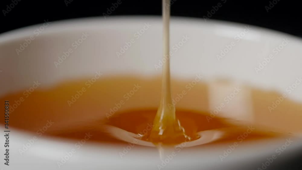 Close up of pouring honey on black background Close up of pouring honey on black background