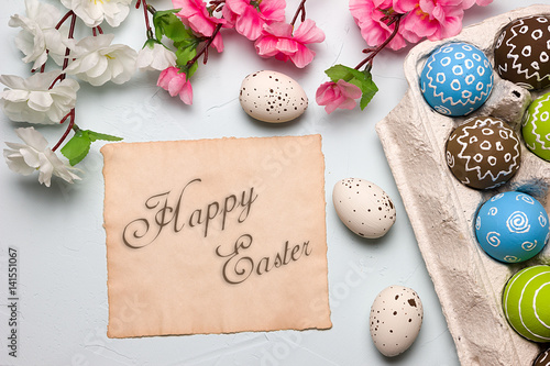 Painted easter eggs and branches of spring sakura closeup on a light blue background with space for congratulation