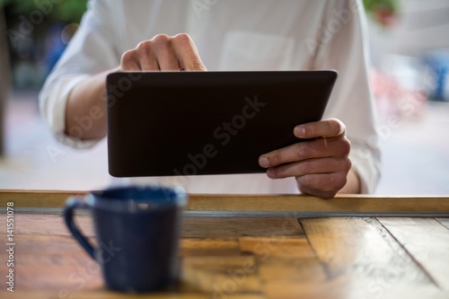 Mid-section of man using digital tablet at counter